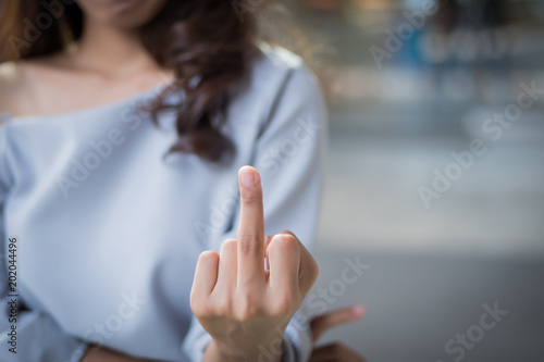rude woman hand giving middle finger to you; negative angry upset failed asian woman showing offensive, rude, f, vulgar middle finger hand gesture; asian woman young adult hand model