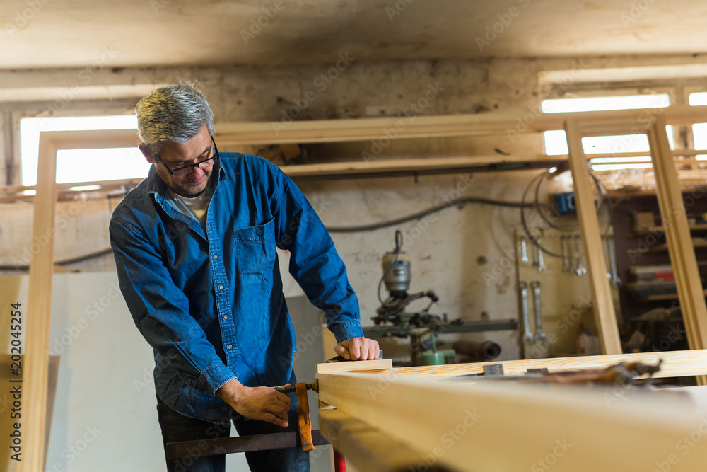 Mid-age carpenter in his workshop Mid-age carpenter in his workshop