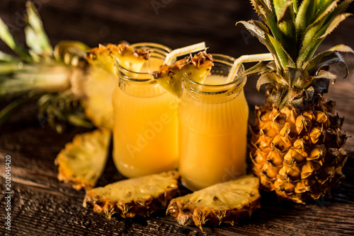Pineapple juice and slice placed on a wooden table