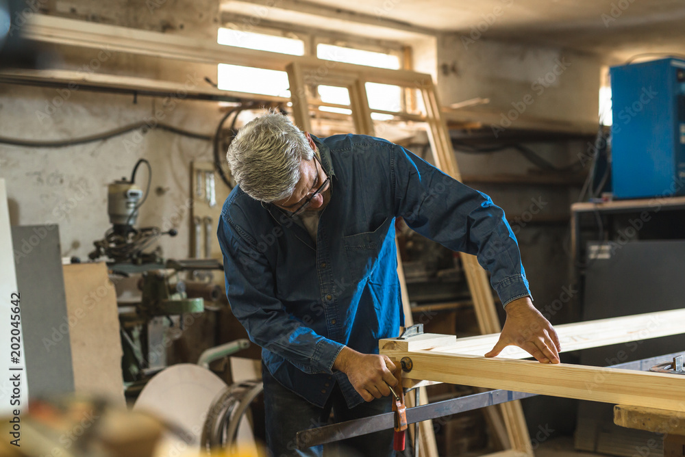Mid-age gray hair carpenter working in his workshop Mid-age gray hair carpenter working in his workshop