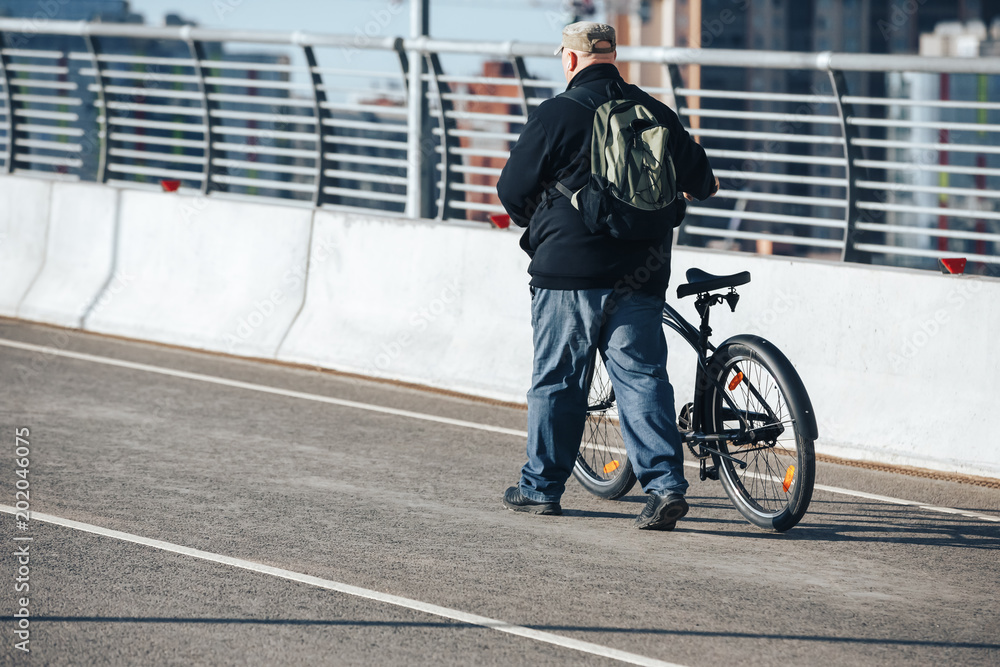 A complete man is taking a Bicycle along the pedestrian bridge up next to him