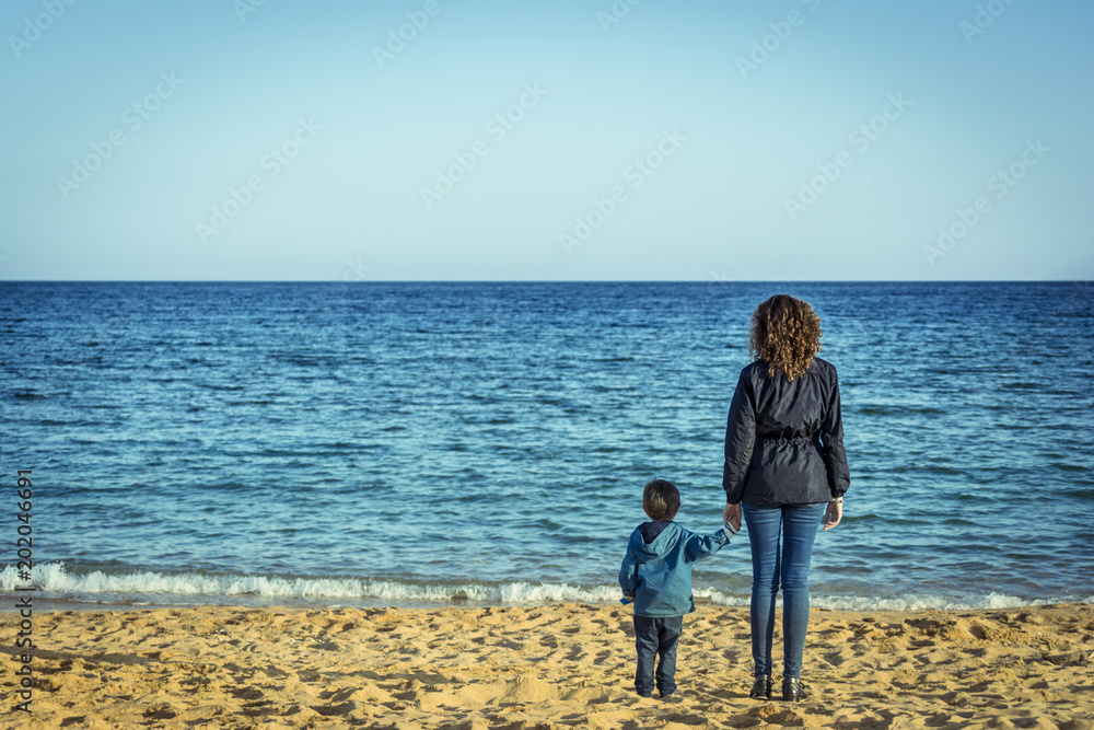 The Bond of a mother and a son, looking at the mediterranean blue sea. Outdoors, lifestyle and family concepts.