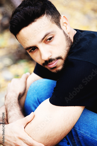 handsome man sitting outside and looking pensive © wernerimages