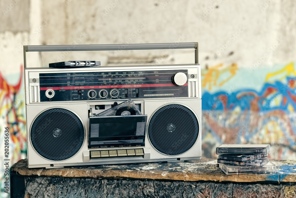 Retro boombox radio with cassettes / Vintage ghetto blaster with plenty of  musical cassettes on grungy background with graffiti. Stock Photo | Adobe  Stock