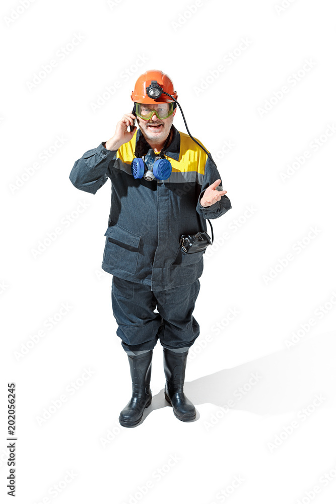 The studio shot of senior bearded male miner standing at the camera on a white background. The studio shot of senior bearded male miner standing at the camera on a white background.