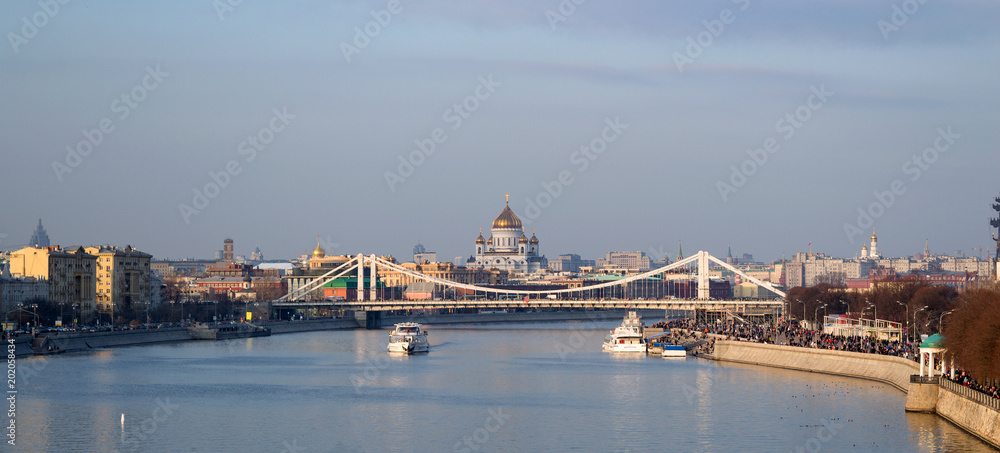 Panoramic view of Moskva river with river buses from Novoandreevskiy Bridge. Krymsky bridge and Cathedral of Christ the Savior on the horizon. Urban landscape on spring evening in Moscow, Russia