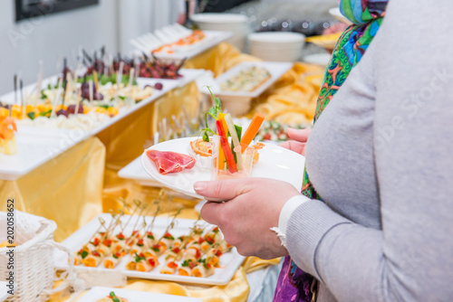 Catering buffet table with food and snacks for guests of the event. Group of people in all you can eat. Dining Food Celebration Party Concept. Service at business meeting, weddings. Selective focus.