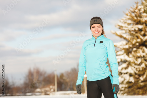 Standing girl wearing winter sportswear, trees background © Voyagerix