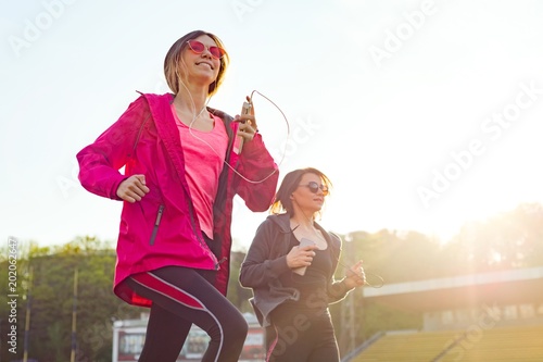 Running sporty mature mother and teen daughter.