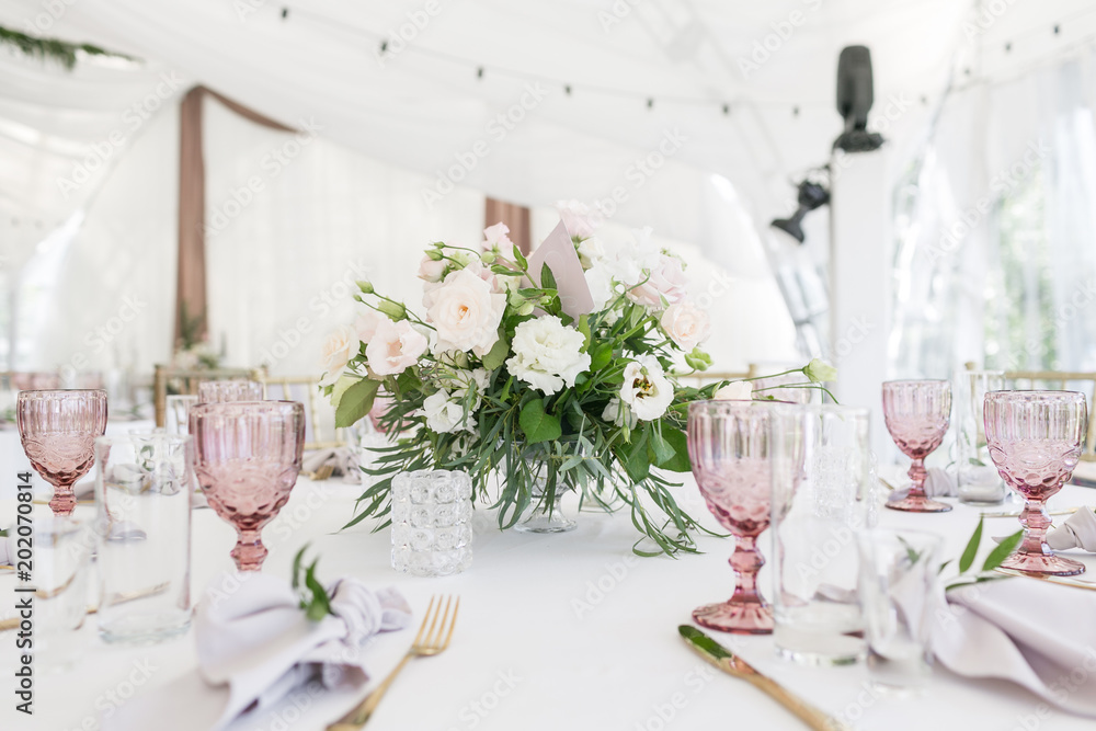 Beautiful table setting with crockery and flowers for a party, wedding reception or other festive event. Glassware and cutlery for catered event dinner.