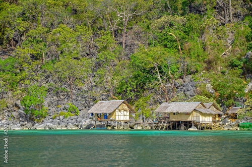 Unapproachable cliffs of Sangat Island and fishing huts by the sea, Busuanga Island, Philippines