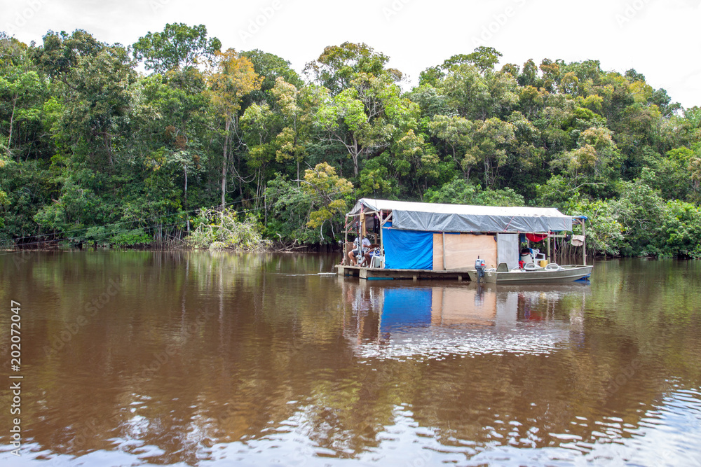 Obraz premium Jungleboat: rustikales selbstgebautes Hausboot / Floß aus Fässern und Planen auf dem Amazonas