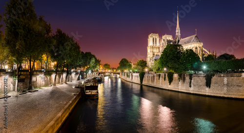 Notre Dame de Paris with cruise ship on Seine river at night in Paris, France © zefart
