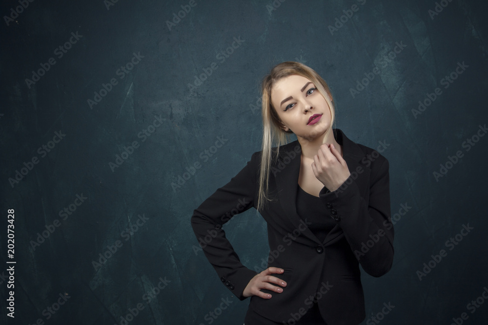 Close-up portrait with lots of details, beautiful smiling woman in black suit against a blue textural wall background with place for text. Close-up portrait with lots of details, beautiful smiling woman in black suit against a blue textural wall background with place for text.