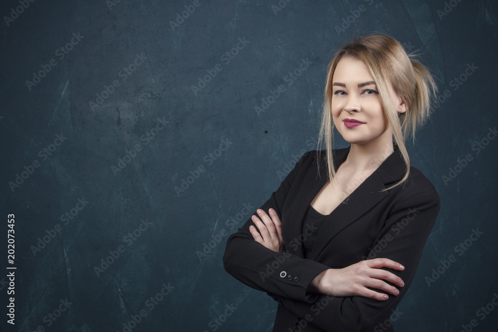 Close-up portrait with lots of details, beautiful smiling woman in black suit against a blue textural wall background with place for text.