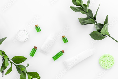 Organic skin care products. Cream, lotion, tonic. oil near green leaves on white background top view