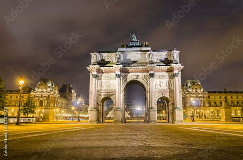 Arc de Triomphe at the Place du Carrousel and Louvre museum in Paris illuminated in the evening