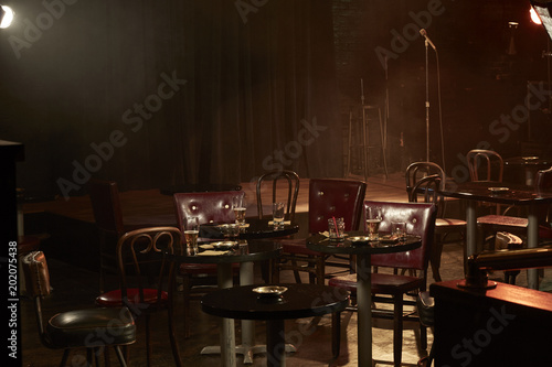 Tables and chairs near stage in empty bar