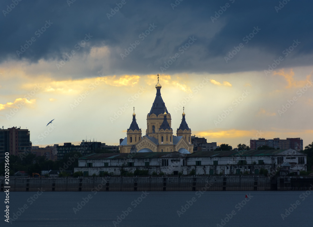 Alexander Nevsky cathedral in Nizhny Novgorod Russia. Stormy sky at sunset. View through the river