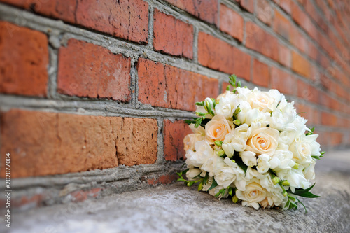 Bouquet of a bride with roses on the background of a red brick wall. Beautiful wedding bouquet. © Мария Аввакумова