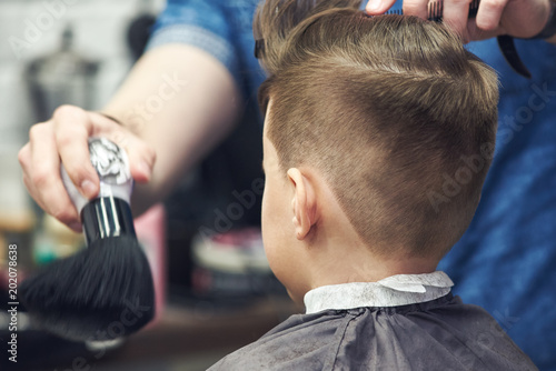 Obraz na płótnie Hairdresser making a hairstyle to a boy in barbershop. w salonie