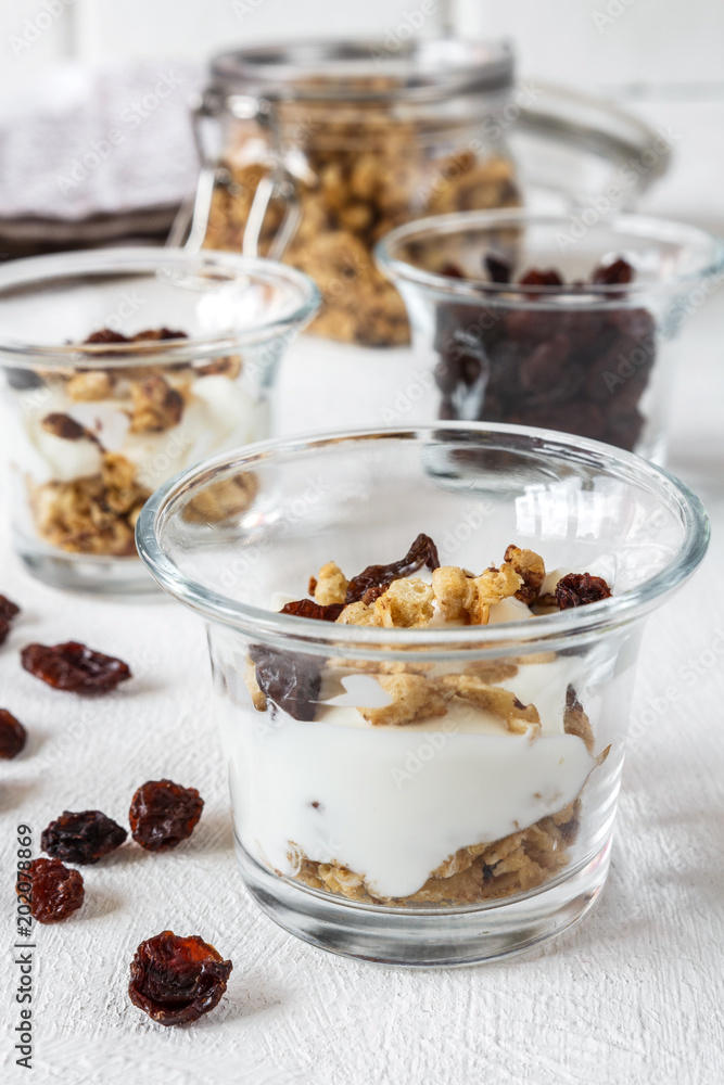 Grnola, raisins, milk in glass jars and various ingredients for a super meal with copy space on a light background Grnola, raisins, milk in glass jars and various ingredients for a super meal with copy space on a light background