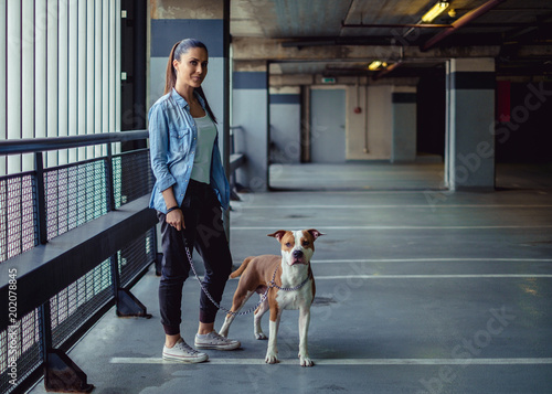Girl holding amstaff dog on a chain in a garage