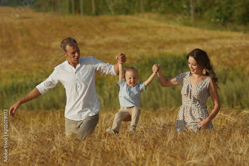 Happy smiling family walking through a wheat field