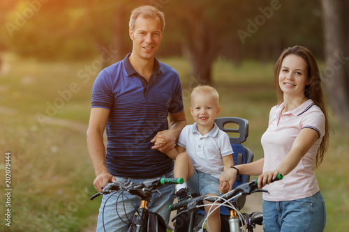 Beautiful bicyclist family, leisure in pine forest, happy parents.