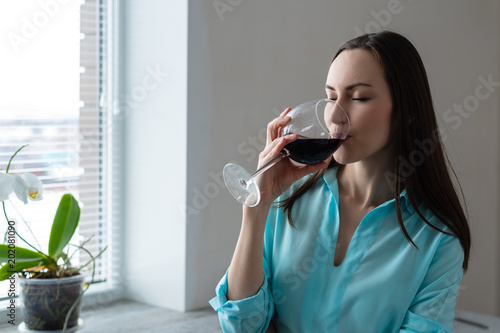 Foto Young woman drinking a glass of red wine