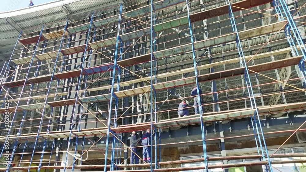 View of building construction site of modern office building surrounded by scaffolding View of building construction site of modern office building surrounded by scaffolding