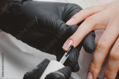 Manicure master applies gel to woman feet in beauty salon.