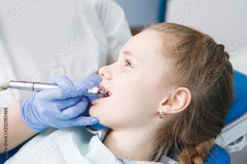 Pediatric dentist examines condition of teeth and braces in child girl.
