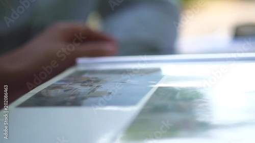 A girl silhouette in pink dress turns photo album pages. A woman tanned skin hands on a table in bright sunlight, close-up. A young couple on summer fresh air picnic.