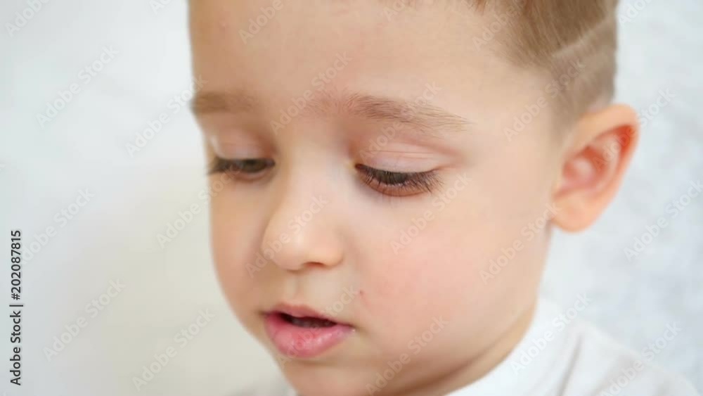 The boy's face is close-up. The child shows neutral emotions, a pensive face The boy's face is close-up. The child shows neutral emotions, a pensive face