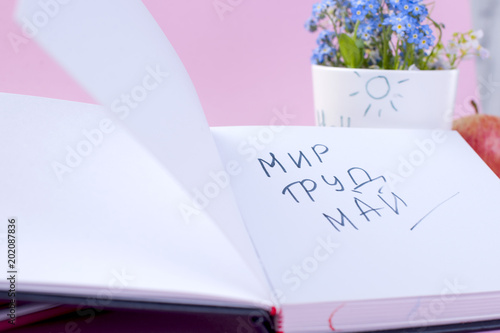 Holiday of Labor and Peace in May. Notepad with text and spring flowers