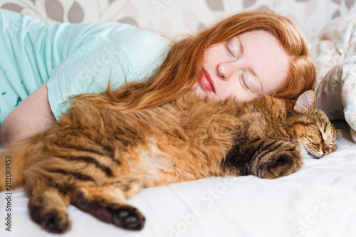 Obraz na plátně Young redhair woman sleeping with cat.