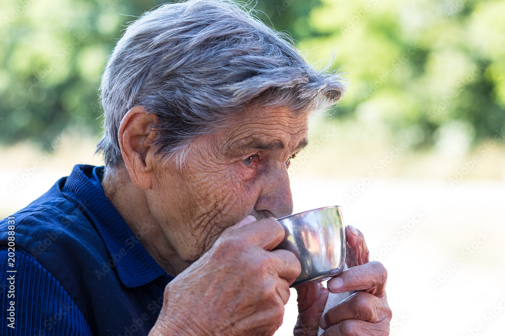 Close up facial portrait of a senior woman drinking tea Close up facial portrait of a senior woman drinking tea