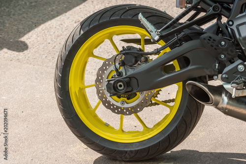 Wheel of a motorcycle with a yellow disk parked in the city, close-up.