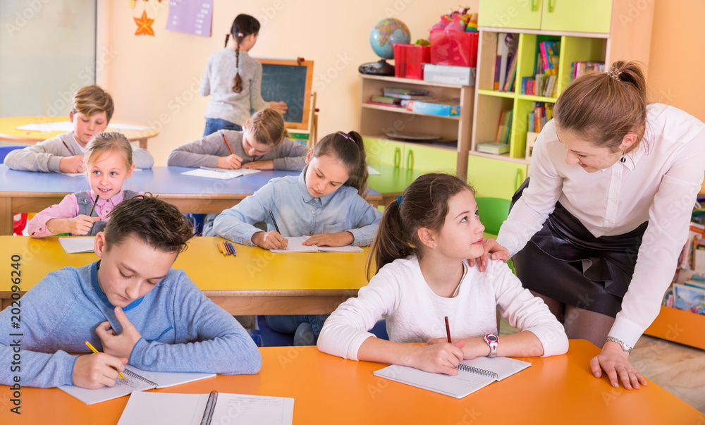 Fototapeta premium Teacher woman helping children during lesson in schoolroom