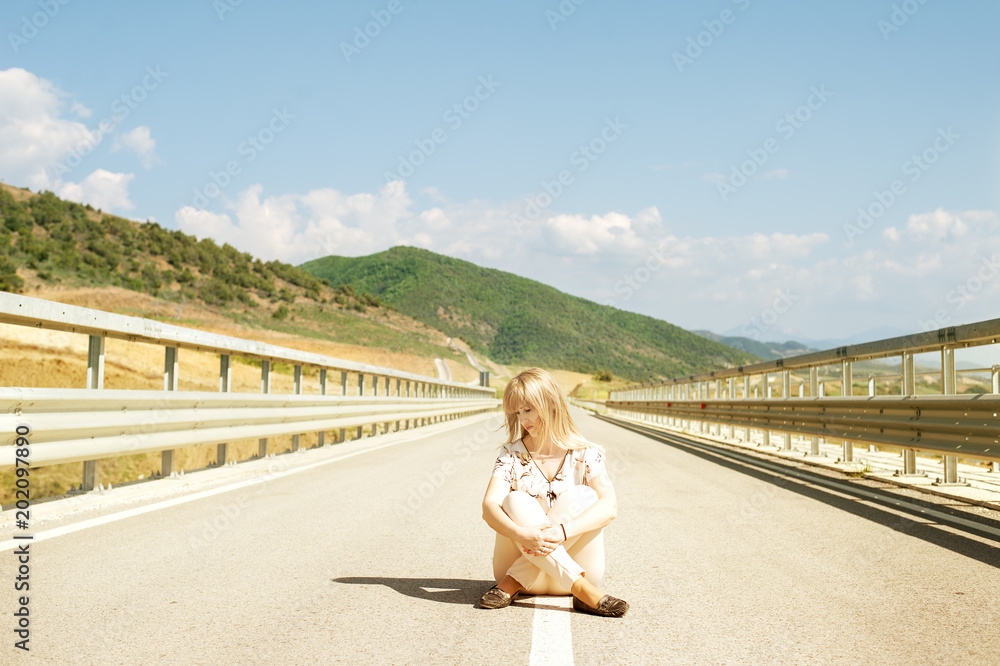 Young woman with closed eyes sitting down on road