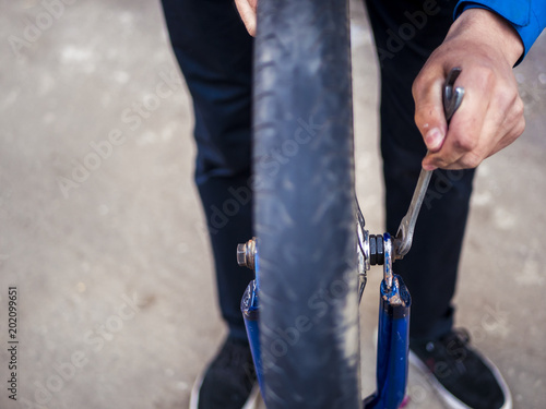 close up bike wheel repairing, hand tighten a nut