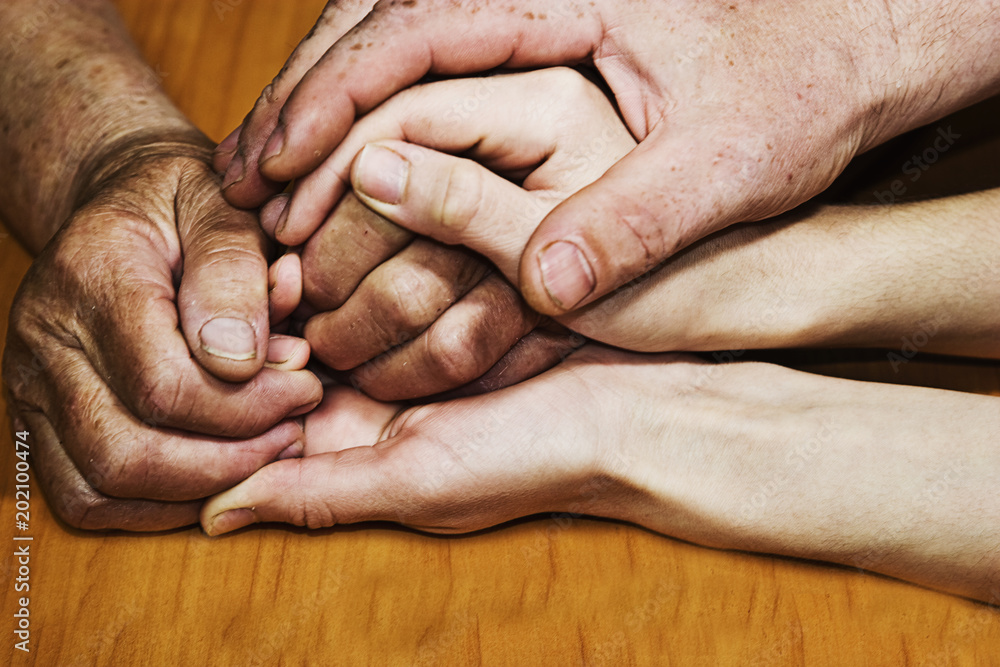 Fototapeta premium The old wrinkled hands of my grandmother with young hands of her granddaughter
