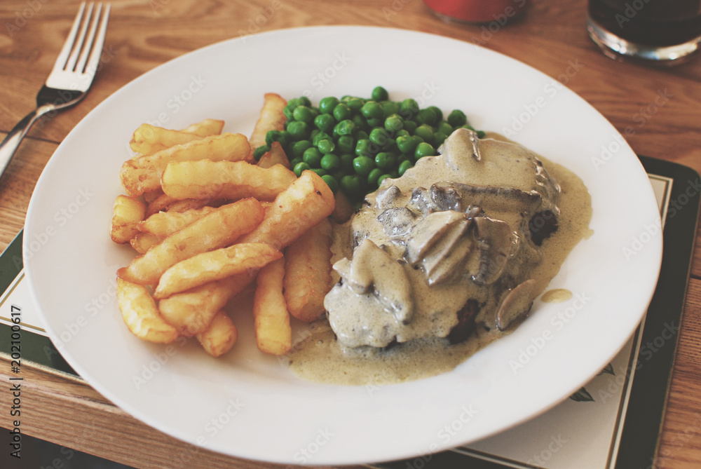 British roasted beef coated with a mushrooms & stilton blue cheese sauce with chips and peas. British roasted beef coated with a mushrooms & stilton blue cheese sauce with chips and peas.