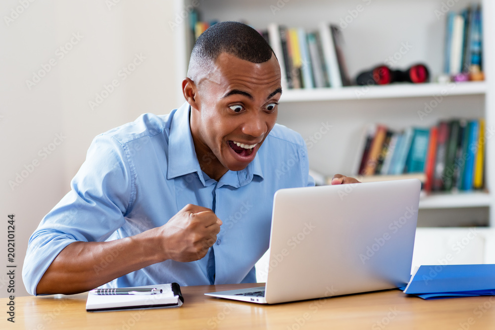 Cheering african american man at computer Cheering african american man at computer