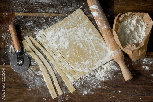 Wallpaper Mural Top view of a dough stripped pastry for cooking homemade pasta recipe on a wooden table background, home cooking concept, close-up, flat lay. Torontodigital.ca