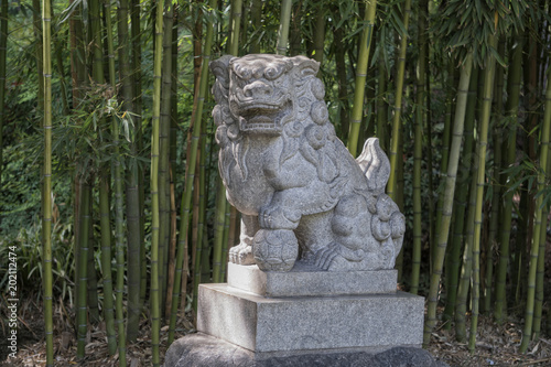 Statue of Chinese guardian lion in a bamboo forest