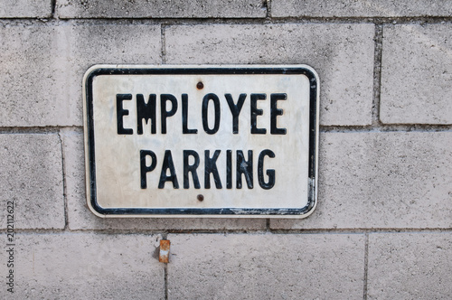 Employee parking sign on the white concrete brick wall