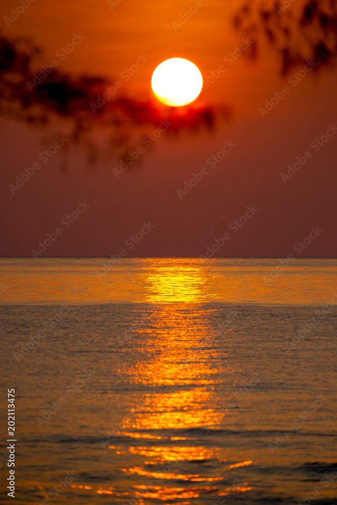 Beautiful big red sunrise in the red sky creates its great stunning reflection on the sea surface.