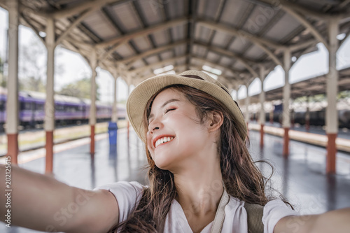 Close-up selfie-portrait of attractive girl with long hair standing at railway statioin